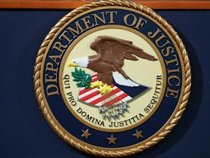 caption: The U.S. Department of Justice seal is seen on a lectern.