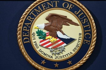 caption: The U.S. Department of Justice seal is seen on a lectern.
