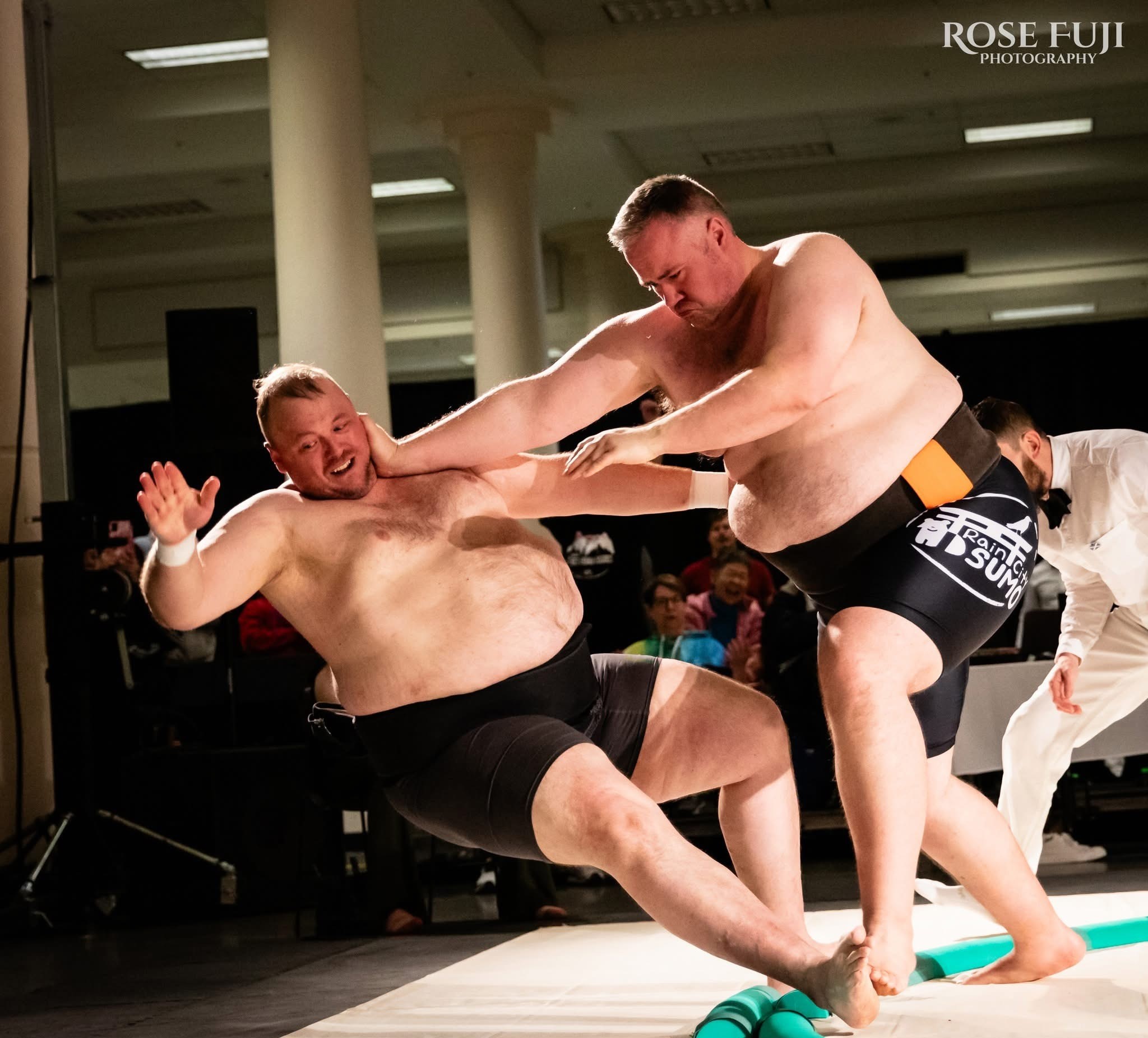 caption: Nick West pushes a fellow Sumo wrestler out of the ring during Rain City Sumo's 2025 tournament in Seattle.
