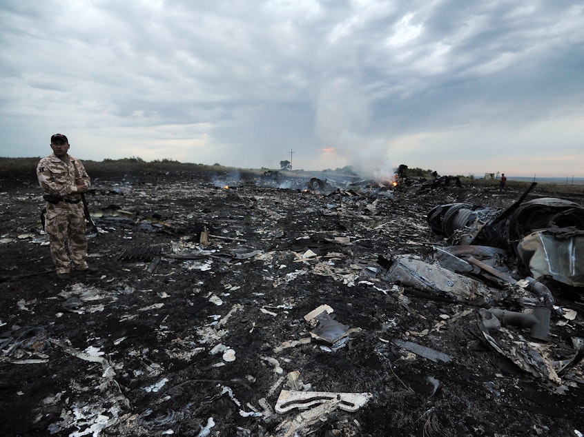 caption: A man wearing military fatigues stands next to the wreckage of Malaysia Airlines MH17 carrying 298 passengers and crew, that crashed in eastern Ukraine six years ago.