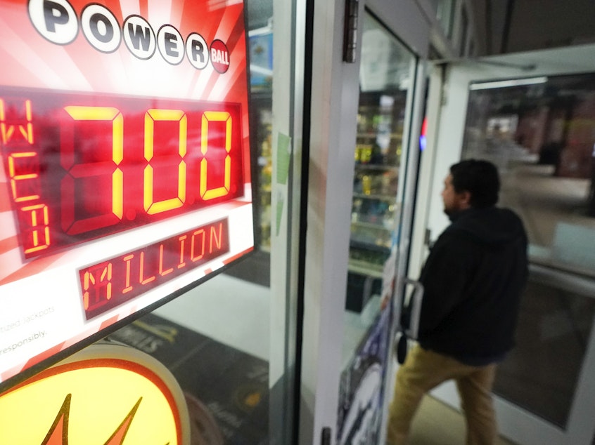 caption: A patron enters a liquor store as a sign displays the Powerball jackpot, Tuesday, Oct. 25, 2022, in Baltimore.