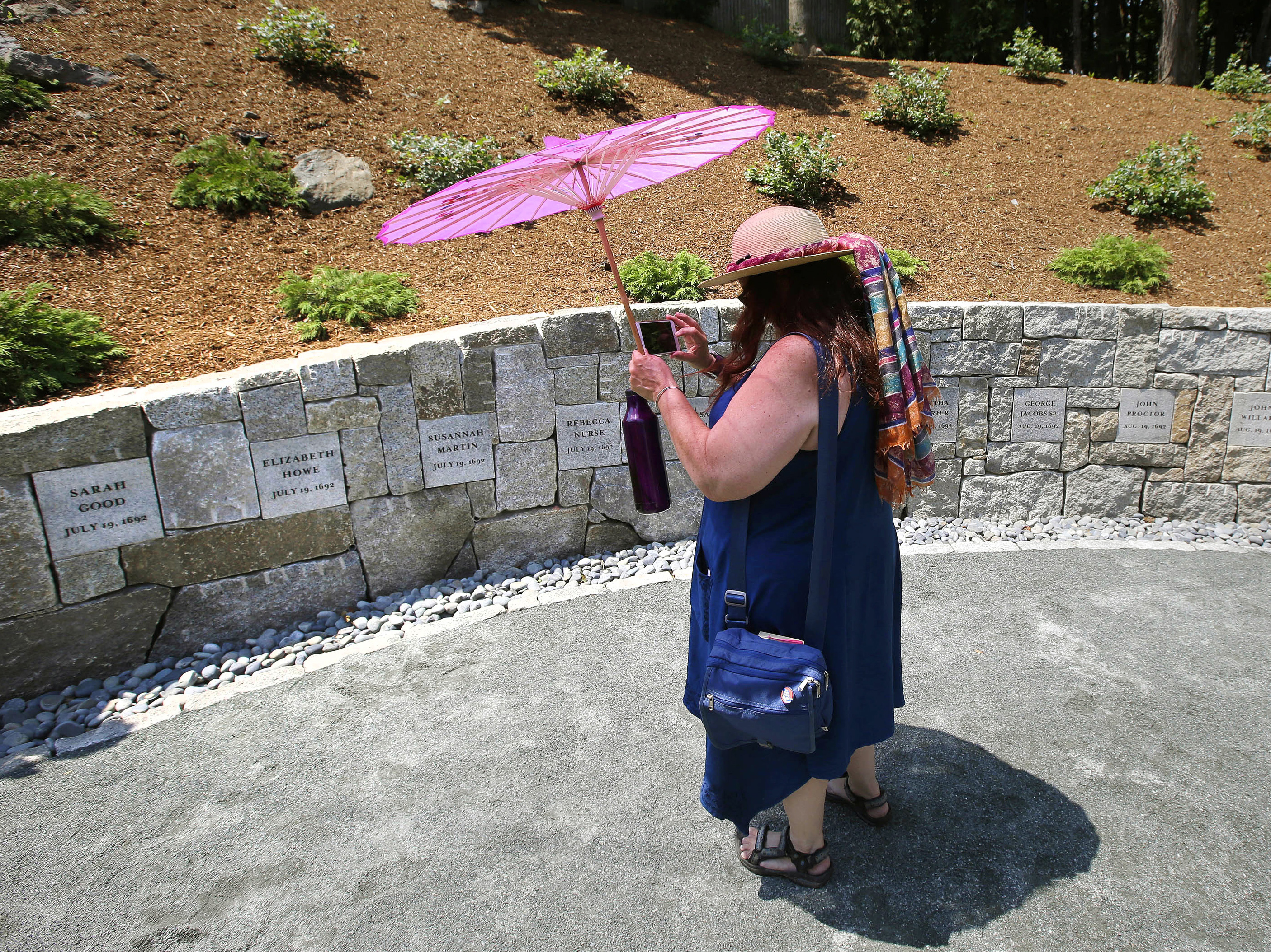 caption: Karla Hailer, a teacher from Scituate, Mass., takes a video on July 19, 2017, where a memorial stands at the site in Salem, Mass., where five women were hanged as witches more than three centuries years earlier. Massachusetts lawmakers on have formally exonerated Elizabeth Johnson Jr., clearing her name 329 years after she was convicted of witchcraft at the height of the Salem Witch Trials.