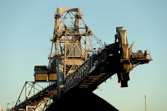 caption: A stacker-reclaimer next to a stockpile of coal at the Newcastle Coal Terminal in Newcastle, New South Wales. Australia is a major coal producer. A new draft agreement at the climate summit in Scotland calls for ending coal power.