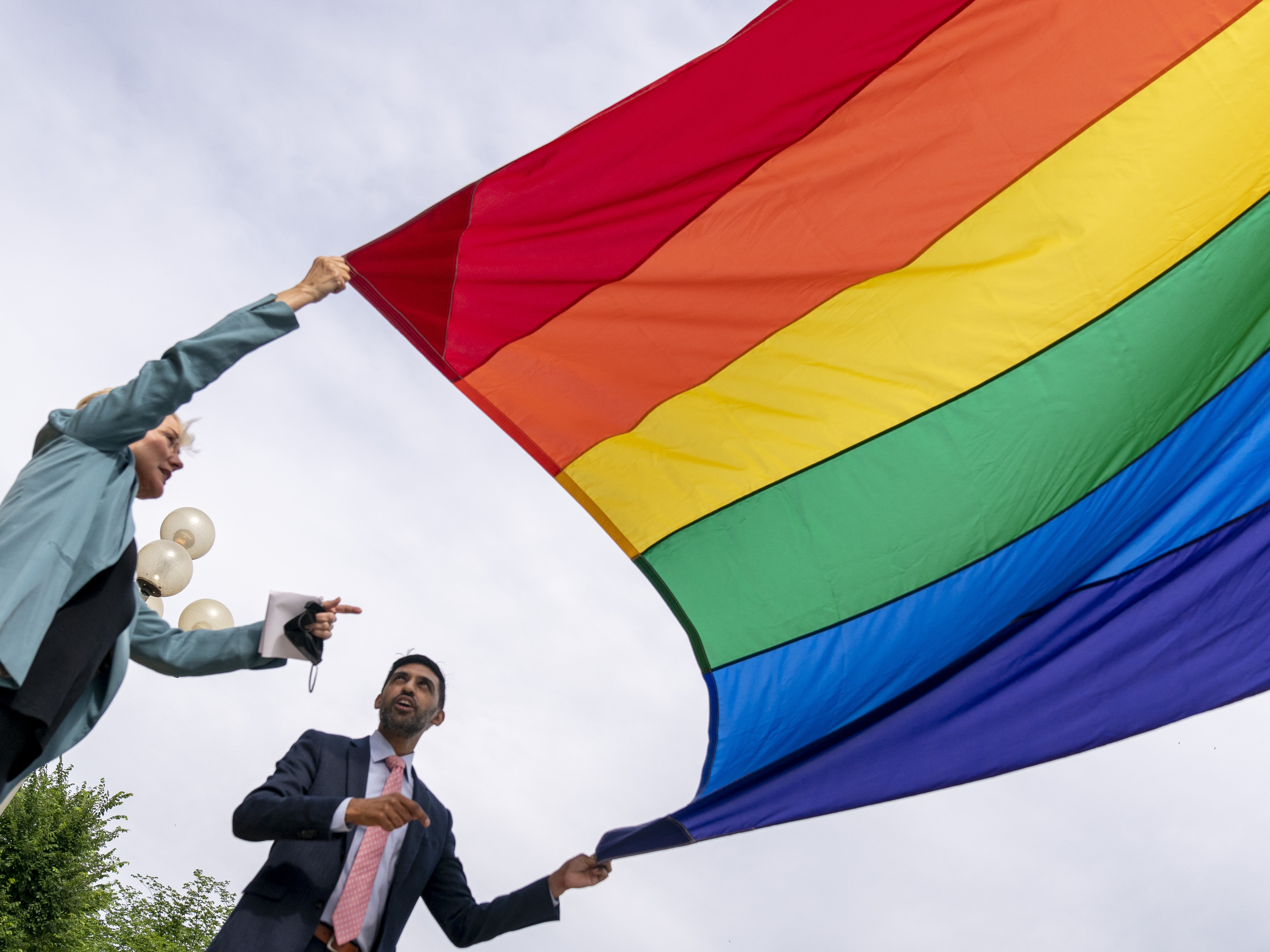 caption: Energy Secretary Jennifer Granholm and Department of Energy Chief of Staff Tarak Shah help raise the Progress Pride Flag outside the DOE in Washington on Wednesday. The Pentagon decided not to allow the flag to fly on military installations for Pride Month.