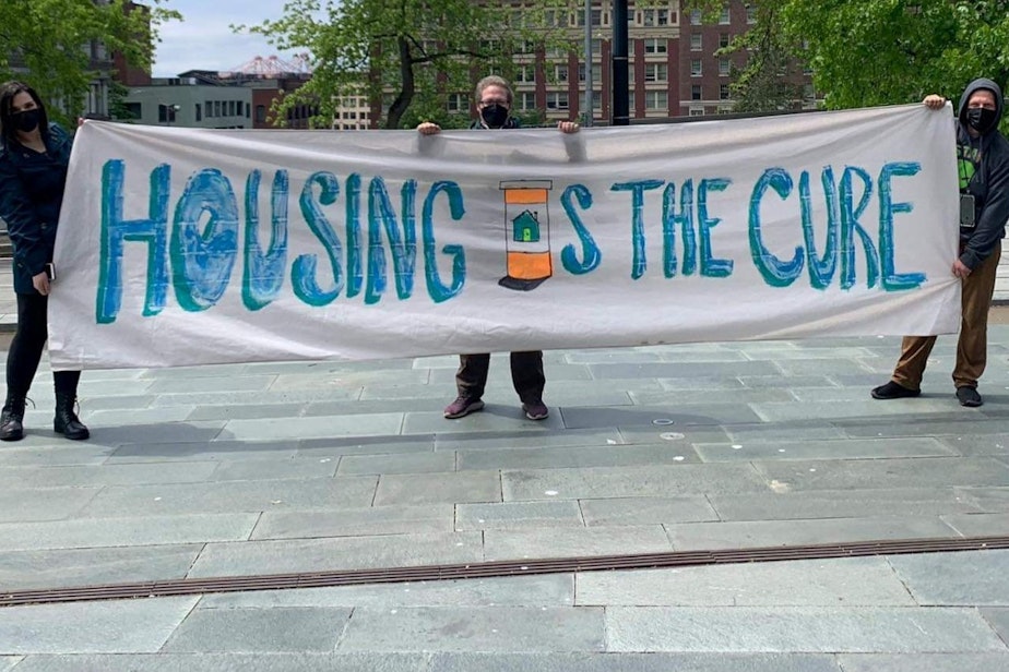 caption: Housing is the Cure banner.