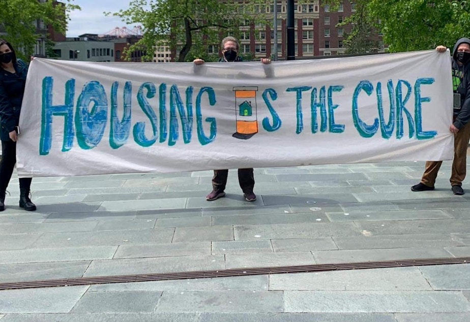 caption: Housing is the Cure banner.