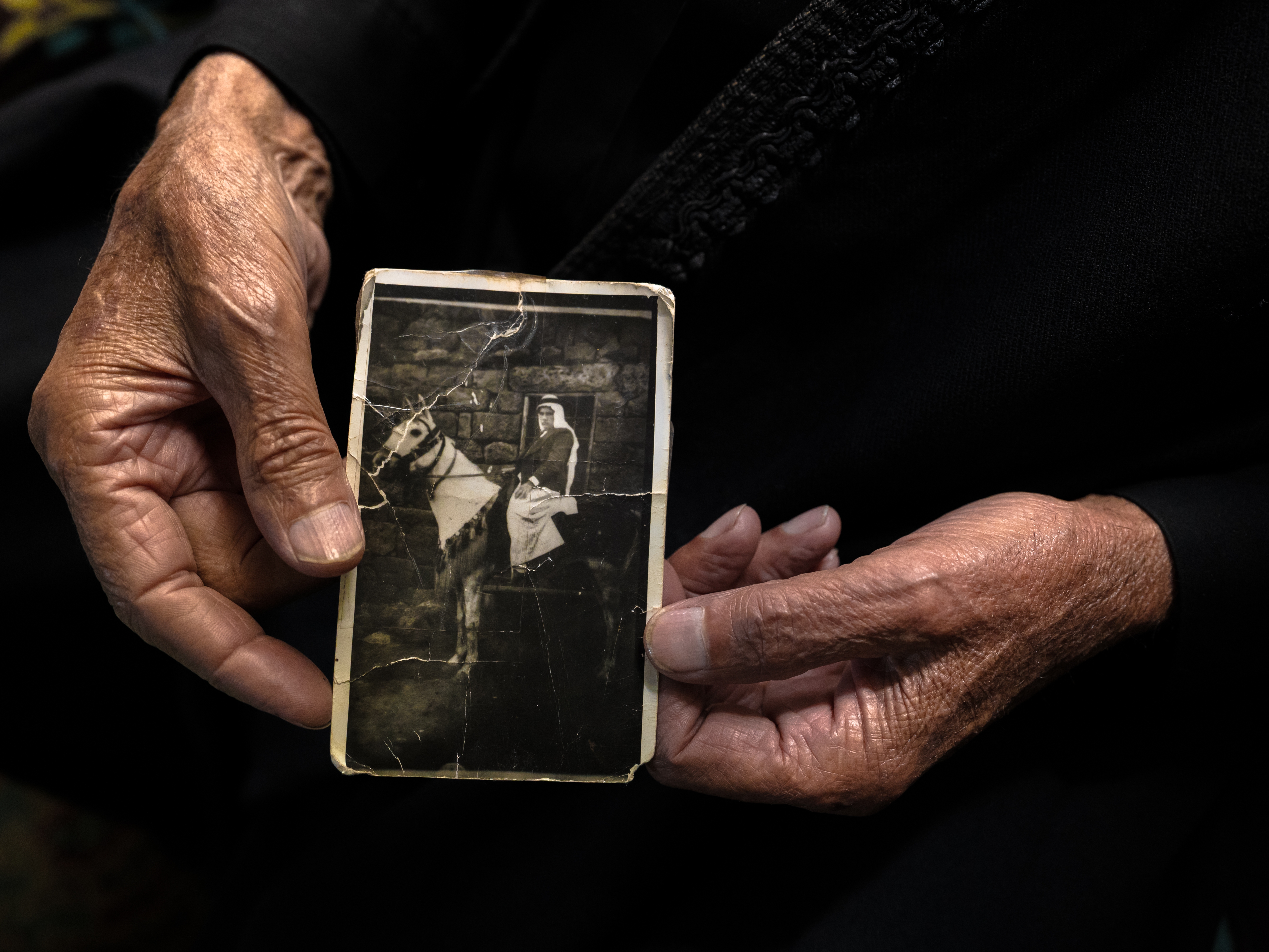 caption: Nawaf Nasr, a 78-year-old member of Syria's Druze community, holds a creased black-and-white photo that he says shows him on horseback in a previous life before he died. The Druze religion holds that reincarnation is a path to spiritual purification.