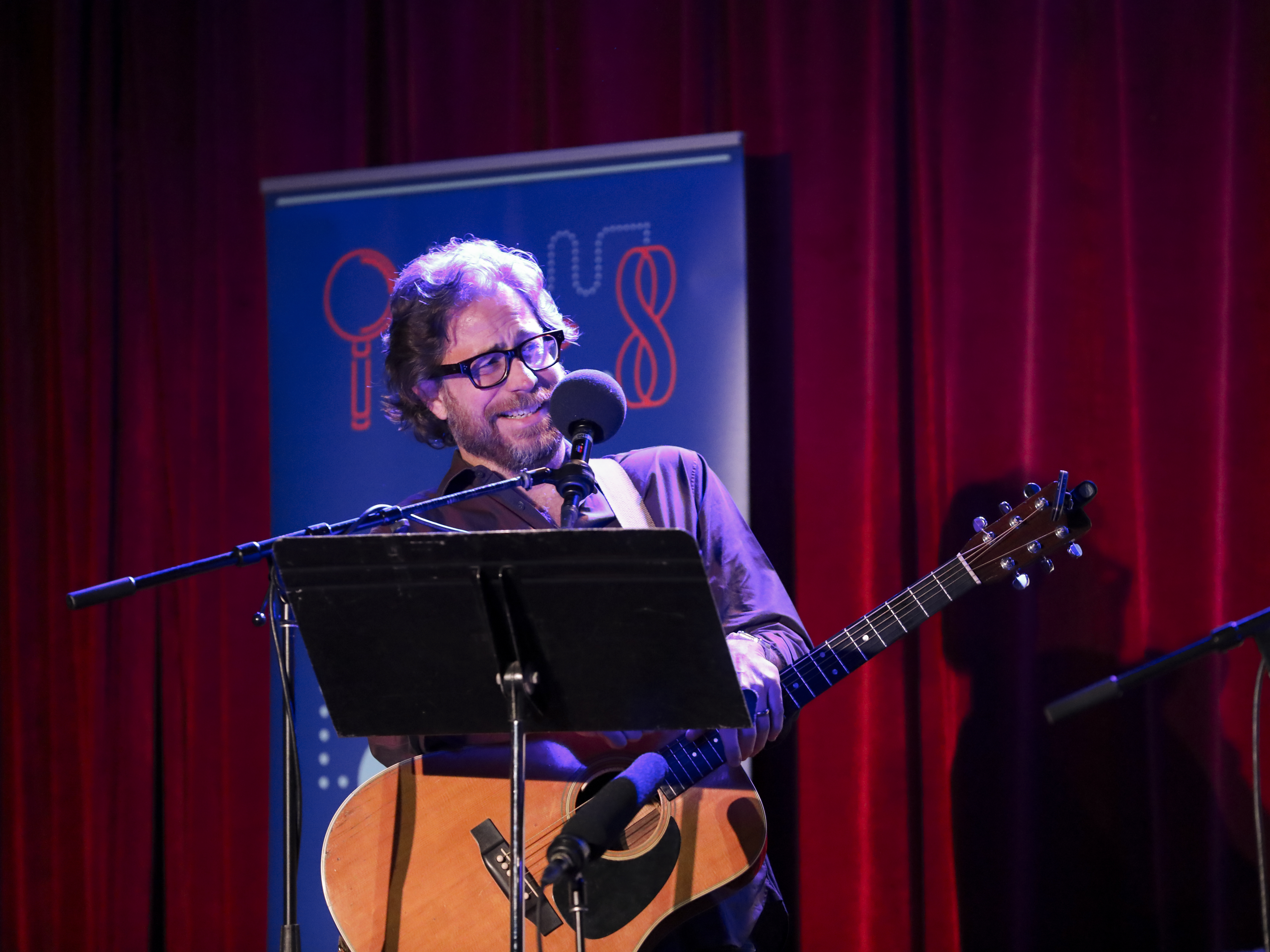 caption: Jonathan Coulton leads a music parody game on <em>Ask Me Another</em> at the Bell House in Brooklyn, New York.