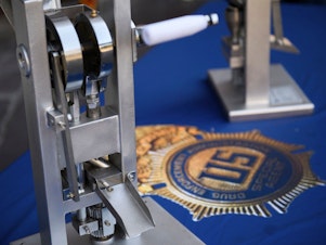 caption: A pill press machine seized by authorities is displayed during a news conference outside the Roybal Federal Building in February 2021 in Los Angeles.