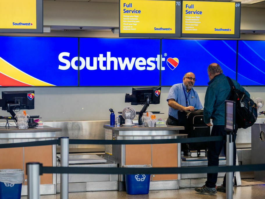 caption: A Southwest Airlines employee assists a passenger during their check-in at the Austin-Bergstrom International Airport on April 18 in Austin, Texas.