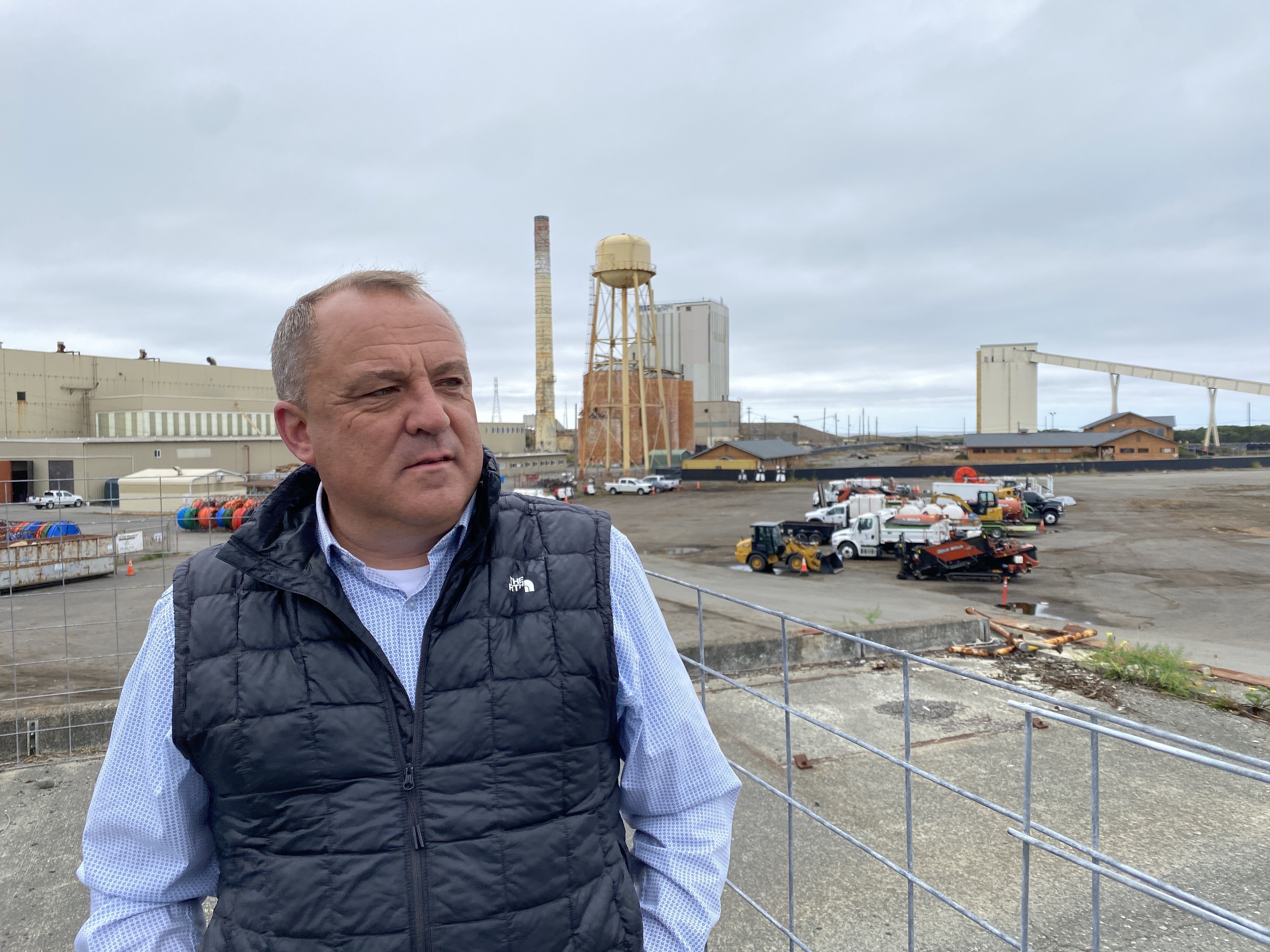 caption: Chris Mikkelsen, executive director of the Humboldt Bay Harbor District, stands on the site of a planned marine terminal in Eureka, Calif. that will assemble wind turbines. The Trump administration recently canceled more than $426 million in federal grants for the port.