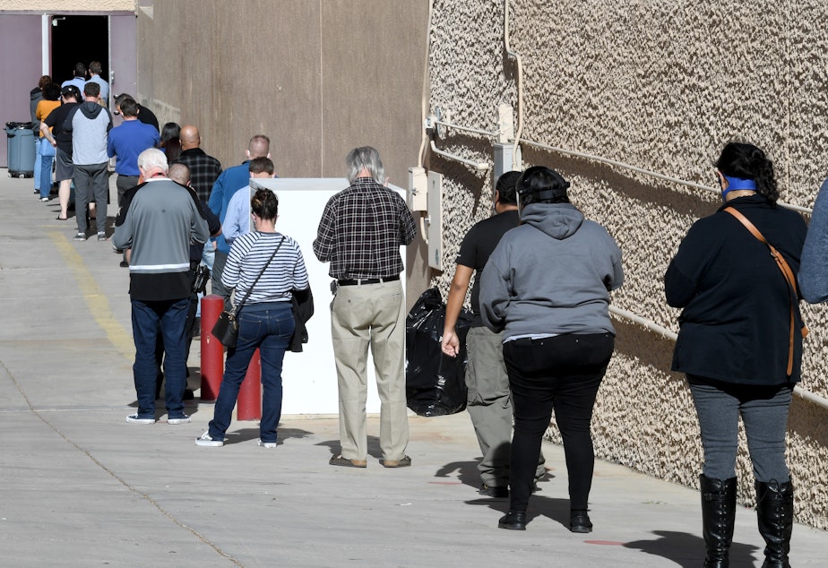 caption: People line up on Thursday for the first day of Clark County's pilot COVID-19 vaccination program at Cashman Center in Las Vegas.