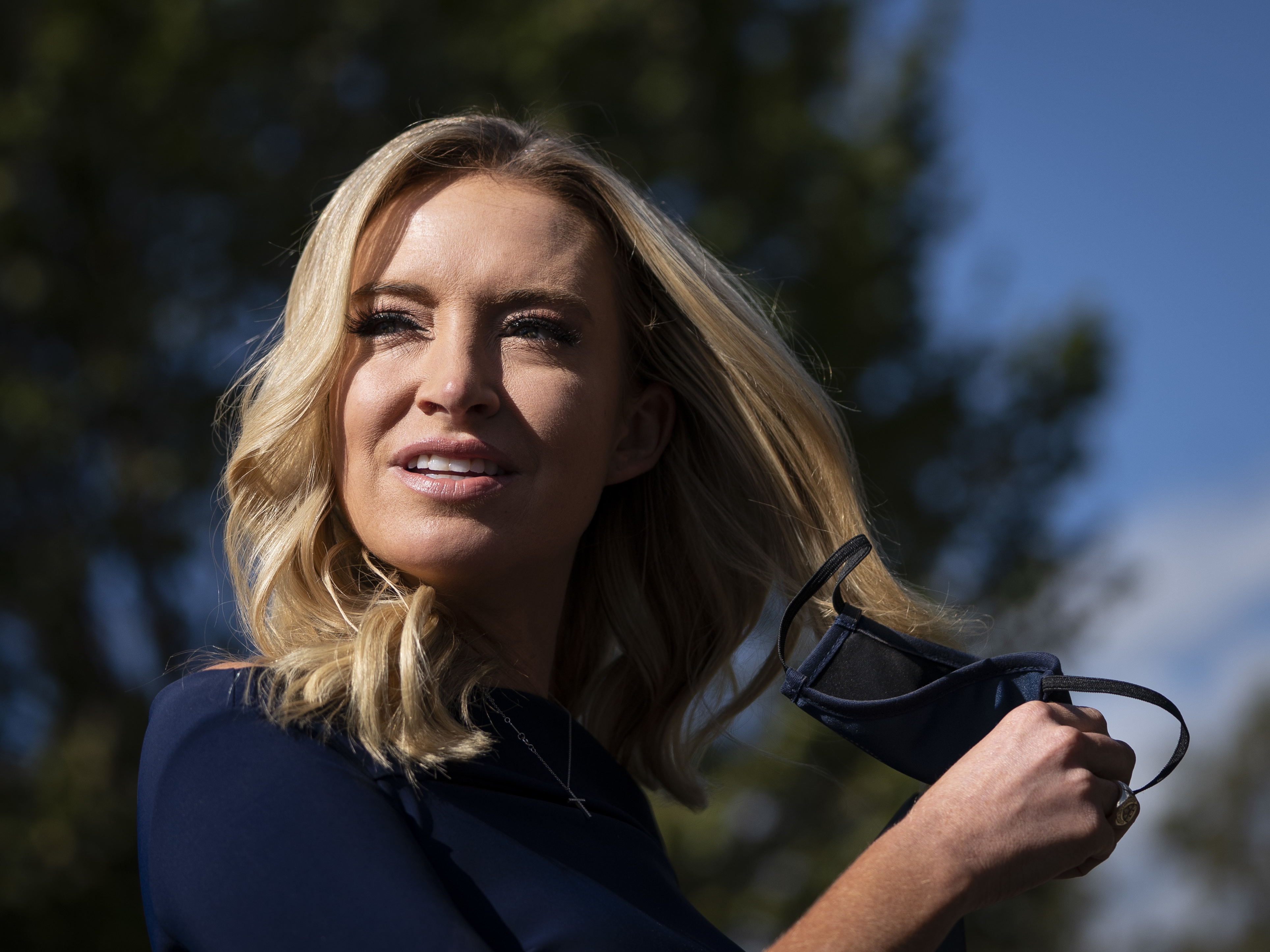 caption: White House press secretary Kayleigh McEnany takes off her face covering before speaking with reporters outside the West Wing of the White House on Friday, the day President Trump announced he had tested positive for the virus.