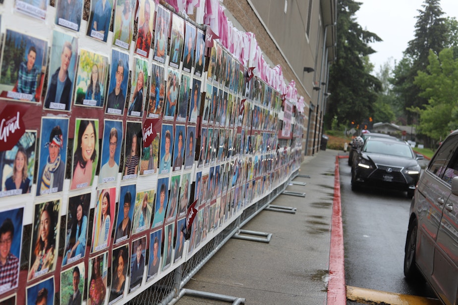 caption: A mosaic of Mercer Island High School seniors’ pictures is on display as cars pass while in line for the drive-through graduation on June 9, 2020. The senior portraits parallel the two-dimensional interactions students have had over video conferencing for the majority of their second semester.