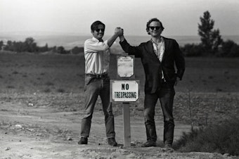 caption: Guadalupe Gamboa (left) and Michael Fox (right) clasping hands the morning after they were arrested for going into a labor camp to help farm workers organize for better living and working conditions.