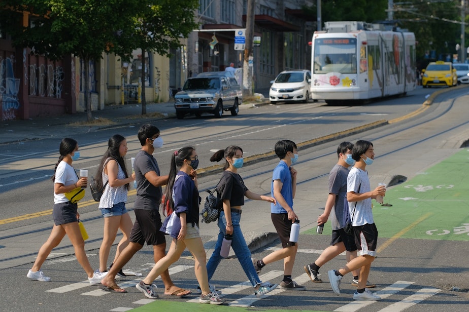 caption: A masked group crosses Broadway in Capitol Hill, Monday, August 2, 2021. With the increase in Covid-19 cases due to the delta variant, many people are still masking up both inside and out.