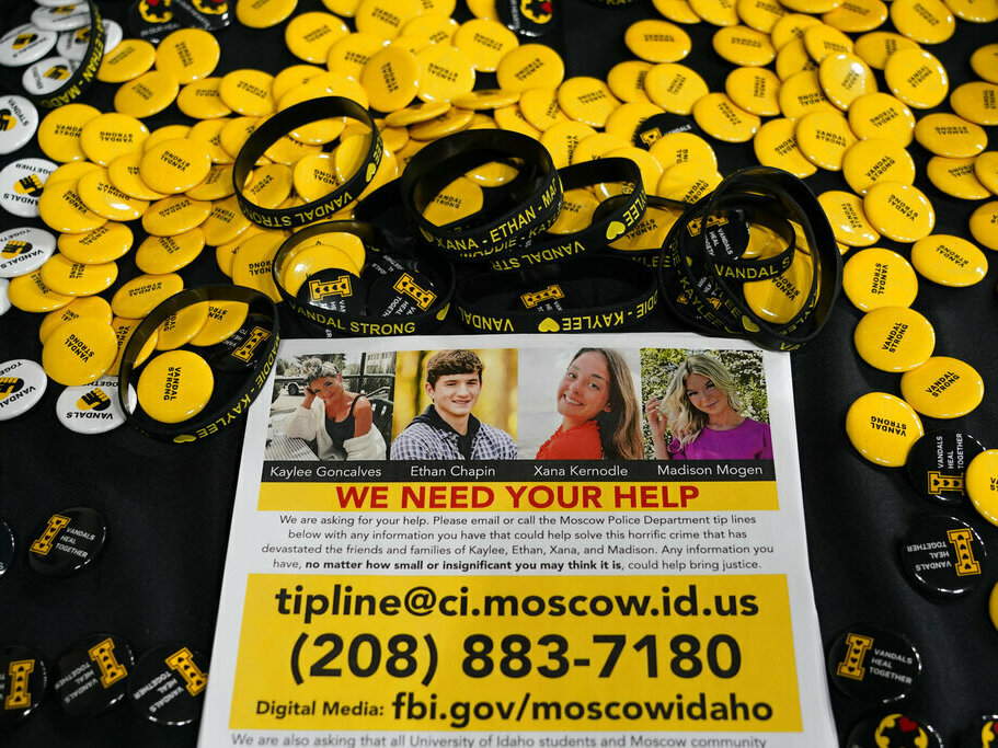 caption: A flyer seeking information about the killings of four University of Idaho students who were found dead is displayed Nov. 30 on a table along with buttons and bracelets during a vigil in memory of the victims in Moscow, Idaho.