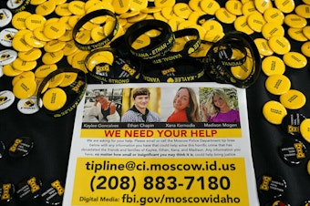 caption: A flyer seeking information about the killings of four University of Idaho students who were found dead is displayed Nov. 30 on a table along with buttons and bracelets during a vigil in memory of the victims in Moscow, Idaho.