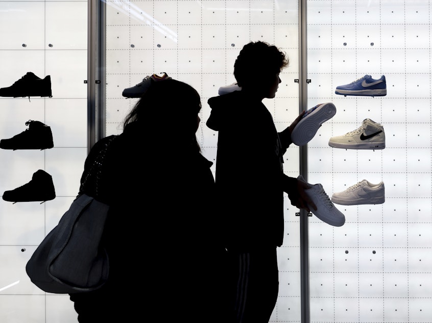 caption: People shop for Nike shoes at a store in New York.