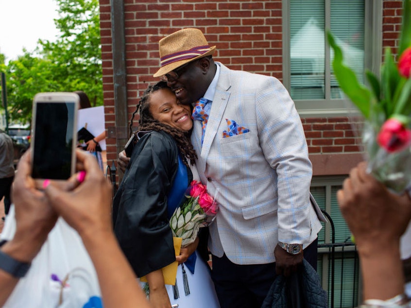 caption: Rashema Melson gets a hug and has her photo taken with her cousin Anthony Young after the 2019 Georgetown University graduation ceremony.