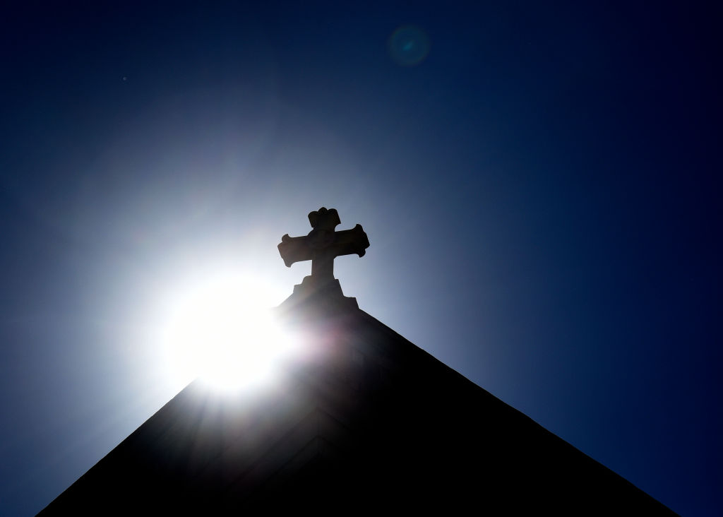 caption: SANTA FE, NEW MEXICO - JUNE 21, 2020:  The sun rises behind a stone cross atop the historic Cathedral Basilica of St. Frances of Assisi in Santa Fe, New Mexico. (Photo by Robert Alexander/Getty Images)