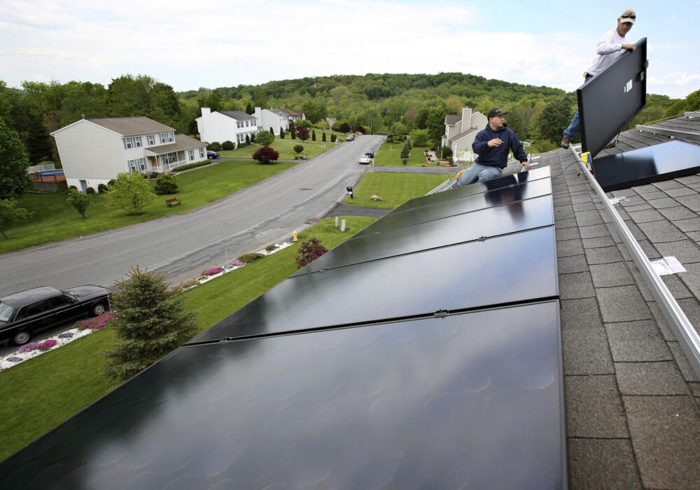 caption: Marco DelTreste, left, and Arsenio Patricio, of Mercury Solar Systems, install panels on the roof of a home in Newburgh, N.Y. (Craig Ruttle/AP)