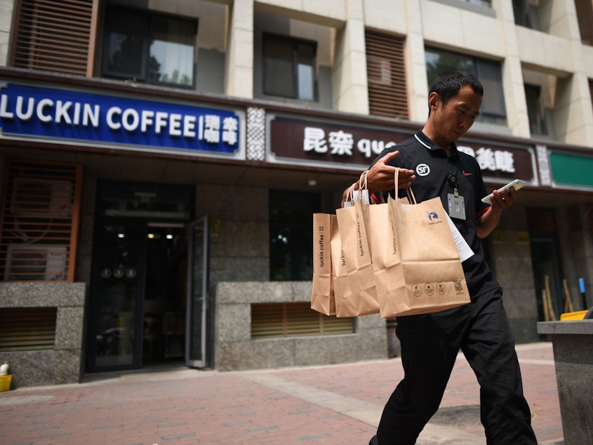 caption: Luckin Coffee customers use an app and can pick up their coffee in three minutes or have it delivered. Above, a deliveryman in Beijing.