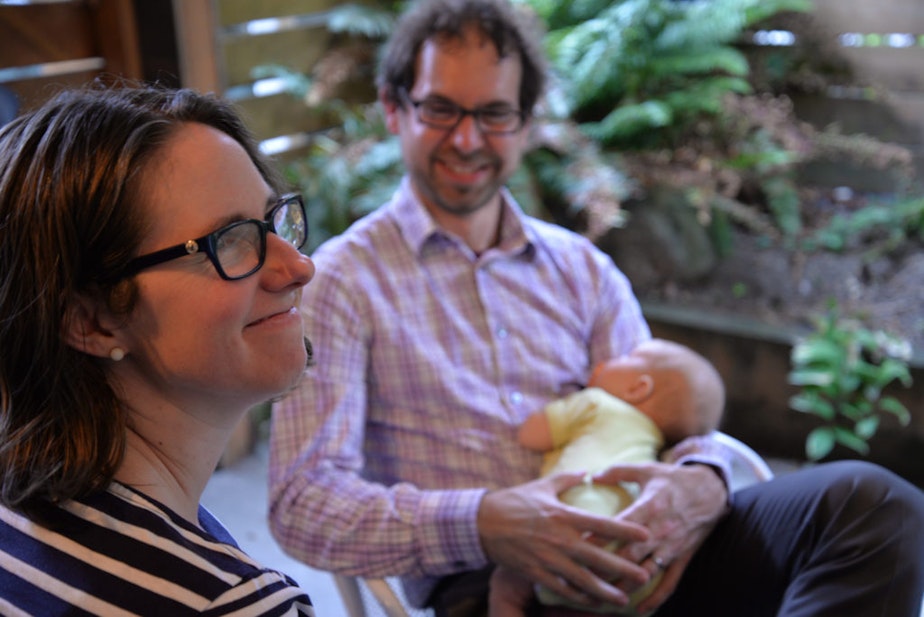 caption: Eddie Minkoff holds his new baby and smiles at his wife Nicole while they talk about their experience with Erika Davis as their doula.