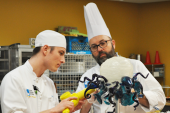 caption: Chef Christopher Harris (right) with student Joey Bale work on a replica of Dale Chihuly's glass chandelier for the artist's birthday cake.