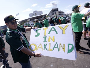 caption: Reuben Ortiz of Modesto, Calif., holds a sign outside Oakland Coliseum to protest the Oakland Athletics' planned move to Las Vegas before the A's game with the Tampa Bay Rays on June 13, 2023. The Athletics' move to Las Vegas was unanimously approved Thursday, Nov. 16, 2023 by Major League Baseball team owners.