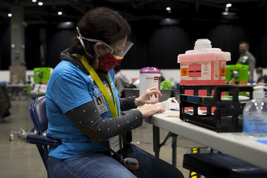 caption: Volunteer Sara Grethlein, the Executive Medical Director for Swedish Cancer Institute, gets ready for the first patients to arrive on Saturday, March 13, 2021, at the new civilian-led mass Covid-19 vaccination site at Lumen Field Event Center in Seattle.