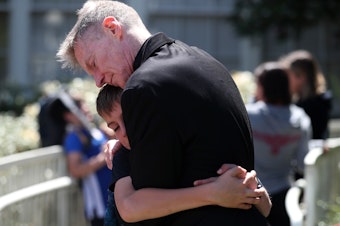 caption: Bryant Elementary 5th-grade student Isaac Plummer hugs kindergarten teacher Kevin Gallagher following a moment of silence on Wednesday, May 15, 2022, at the school in Seattle. 