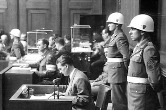 caption: Staff Sgt. Emilio DiPalma (right) stands on guard at the Nuremberg Trials in 1945.