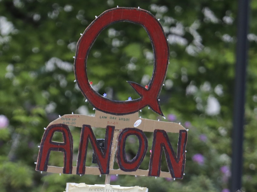caption: A person carries a sign supporting QAnon during a May 2020 protest rally in Olympia, Wash.