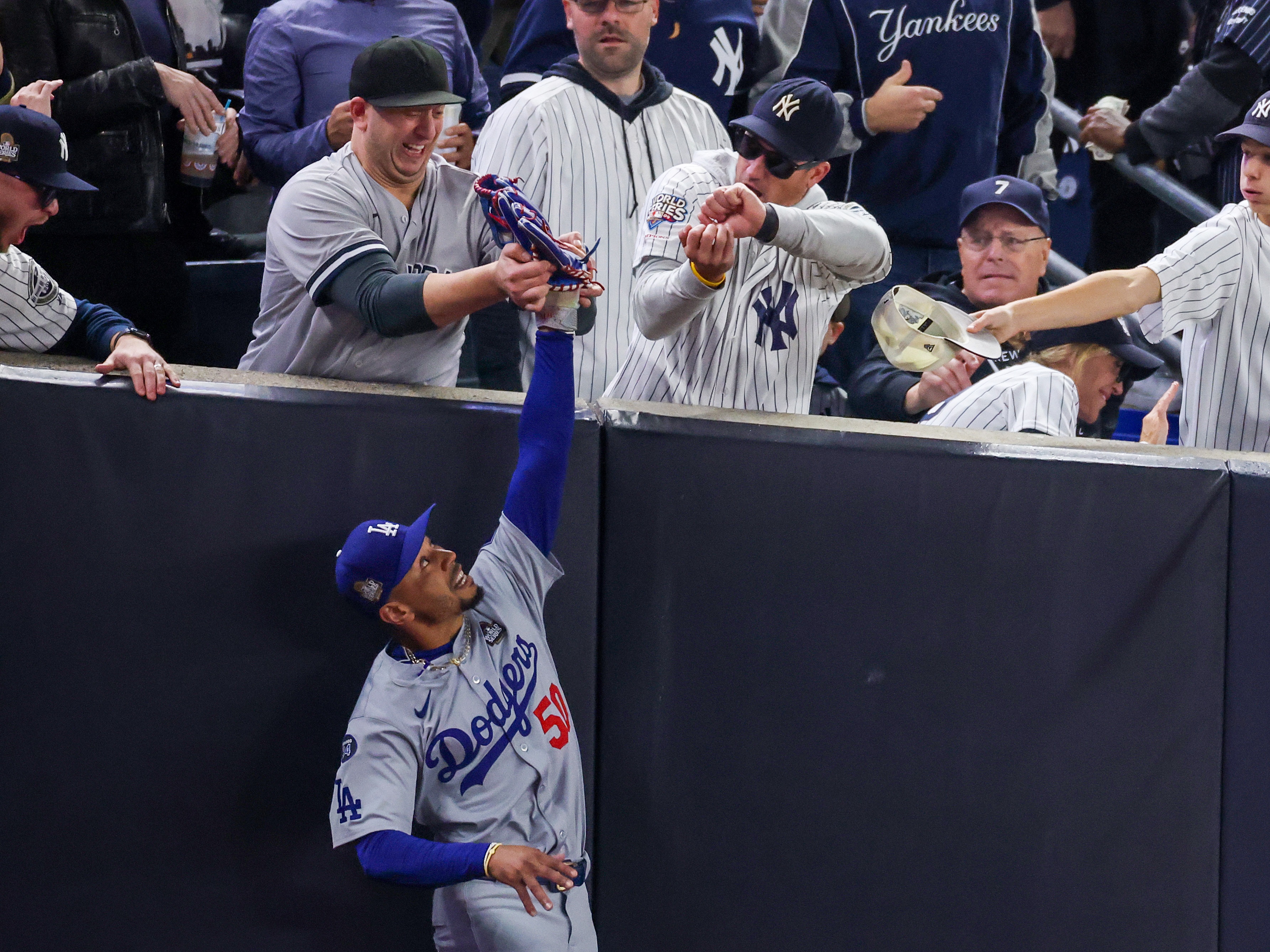 caption: Fans interfere with Mookie Betts of the Los Angeles Dodgers as he attempts to catch a fly ball in foul territory during Game Four of the 2024 World Series against the New York Yankees at Yankee Stadium on Tuesday.