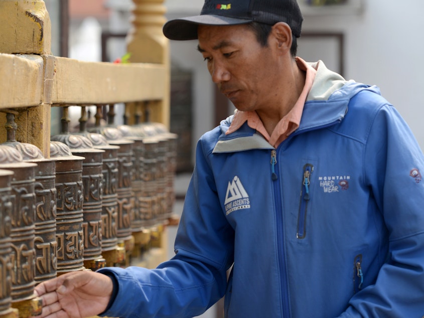 caption: Nepali mountaineer Kami Rita Sherpa hopes to break his own record for climbing Everest, aiming for 25 summits. He's seen here in 2018, spinning prayer wheels in Kathmandu.