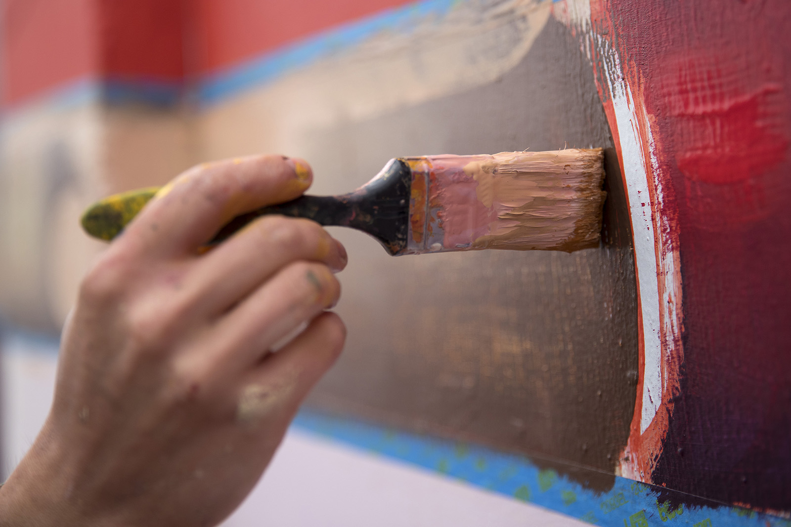caption: Mural artist Zoer paints a mural in September 2017 along the Sodo Track in Seattle as part of a project for 4Culture.