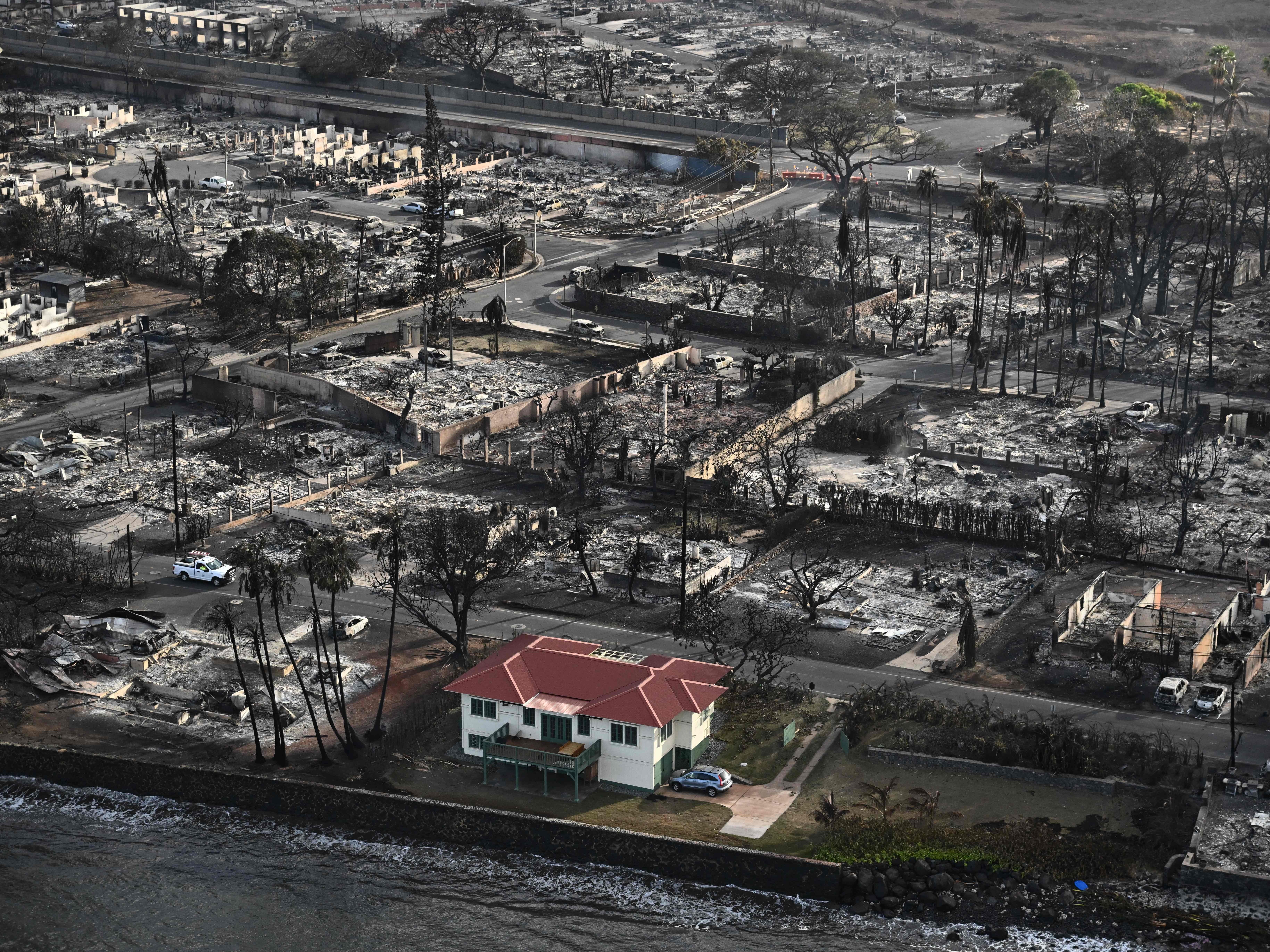 caption: The fire that devastated historic Lahaina in western Maui left a red-roofed house relatively unscathed. Its owner says he wants to open the house to the neighborhood to help the rebuilding process.