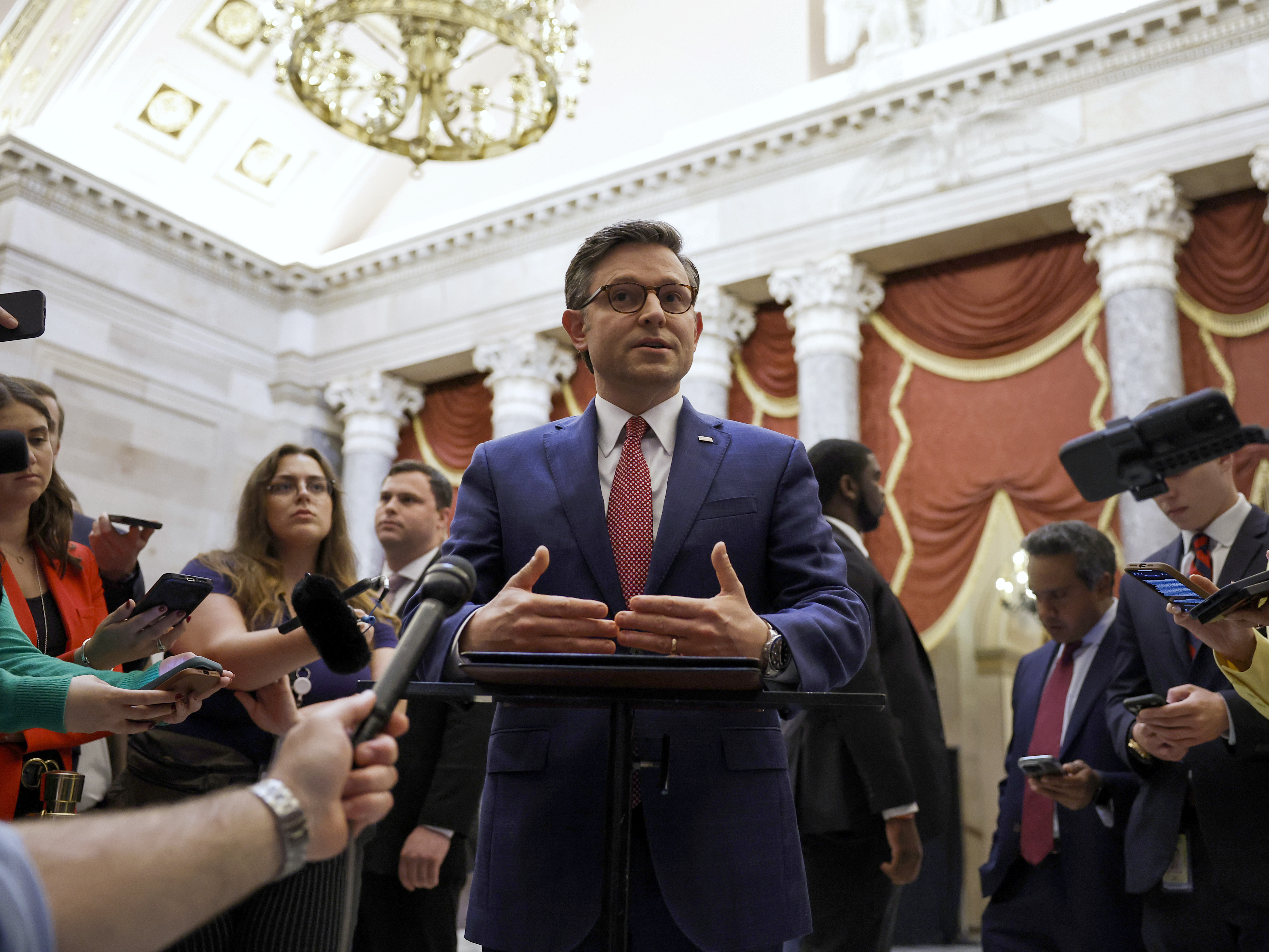 caption: Speaker of the House Mike Johnson speaks with reporters in Statuary Hall after meeting with Reps. Marjorie Taylor Greene and Thomas Massie on May 6.