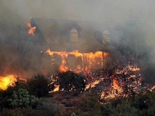 caption: Many homes are destroyed in wildfires due to wind-driven embers that get caught in the landscaping. California is now drafting rules that would limit vegetation within five feet of a house.