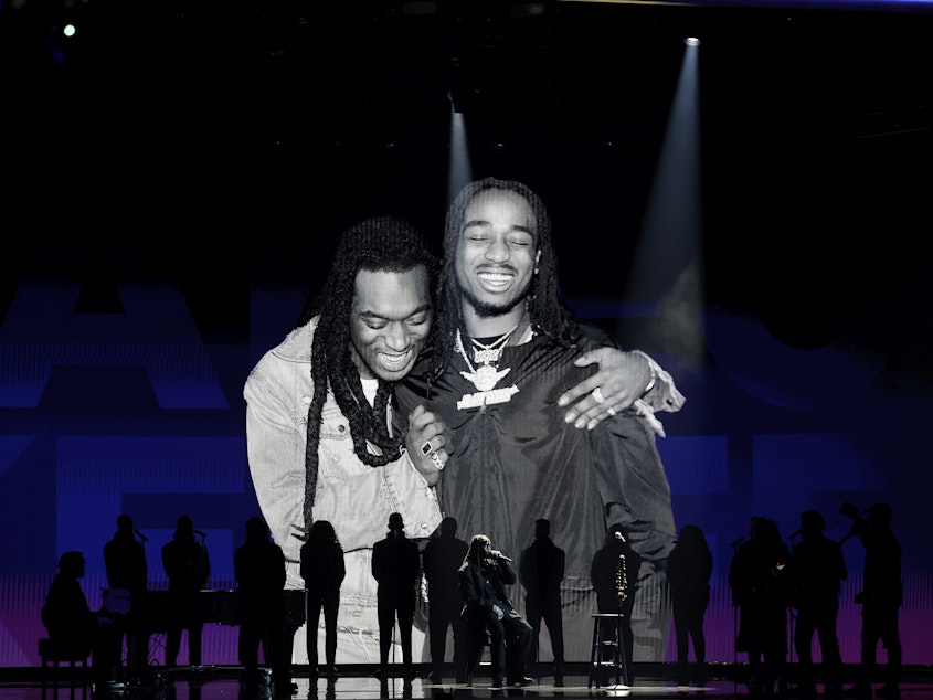caption: Quavo (center, seated) performs while an image of him and the late Takeoff is projected on a screen during the 65th GRAMMY Awards.