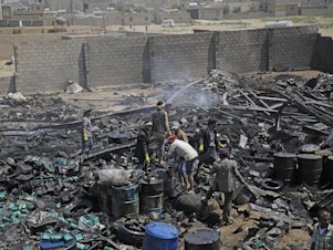 caption: Workers salvage oil canisters from the wreckage of a vehicle oil store hit by Saudi-led airstrikes last July in Sanaa, Yemen. The U.S. said Thursday it will no longer back the Saudi-led military offensive.