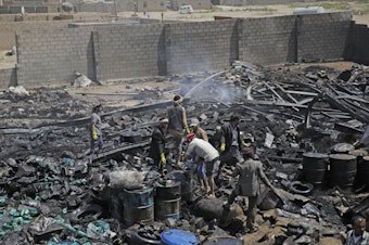 caption: Workers salvage oil canisters from the wreckage of a vehicle oil store hit by Saudi-led airstrikes last July in Sanaa, Yemen. The U.S. said Thursday it will no longer back the Saudi-led military offensive.