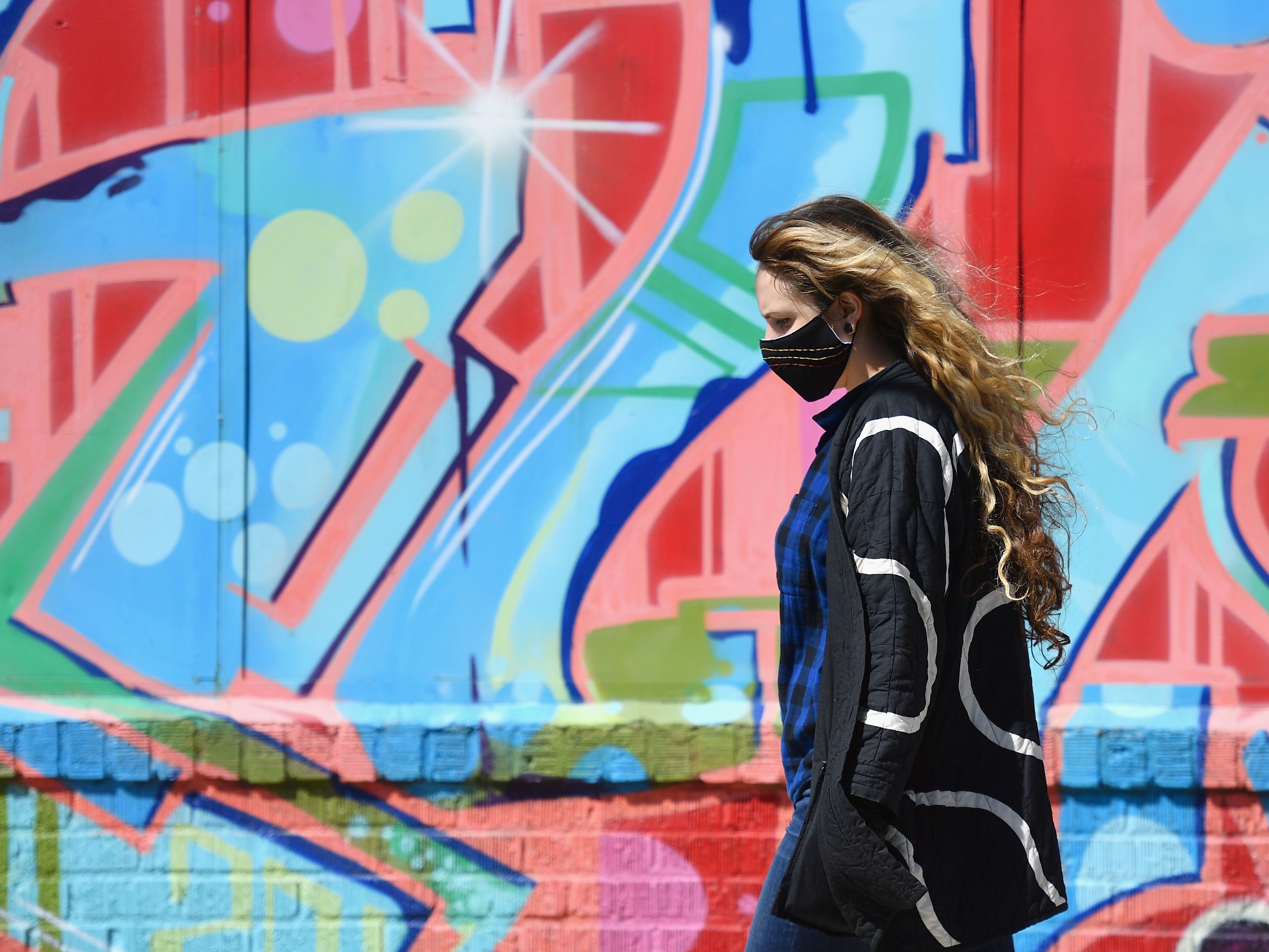 caption: A pedestrian wearing a face covering passes Thursday in New York City. On Saturday, Gov. Andrew Cuomo told reporters that New York continued to see a rise in confirmed cases and deaths related to the coronavirus throughout the state.