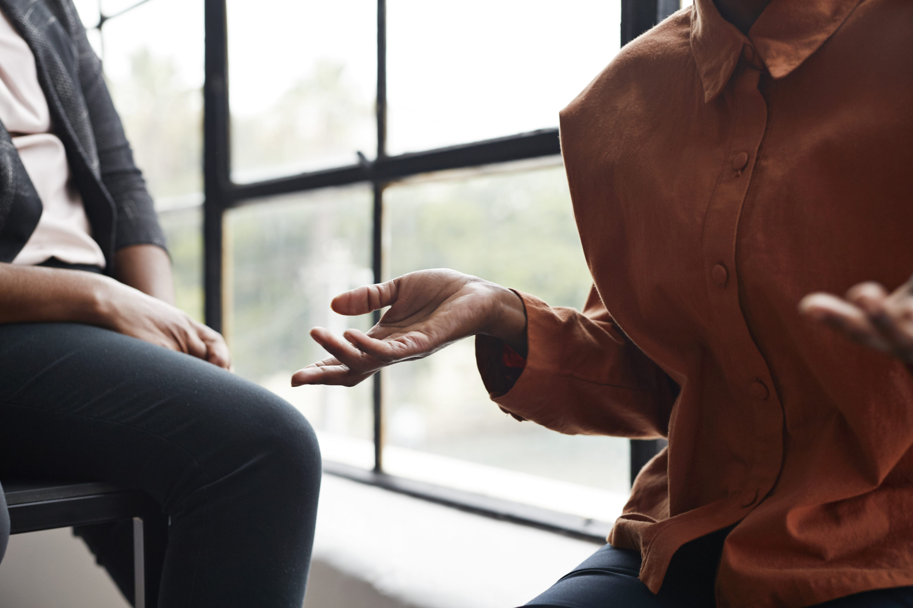 caption: A businesswoman gesturing while sitting by window at workplace. (Getty)