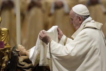 caption: Pope Francis unveils a statue of Baby Jesus as he celebrates Christmas Eve Mass at St. Peter's Basilica, at the Vatican, on Friday.