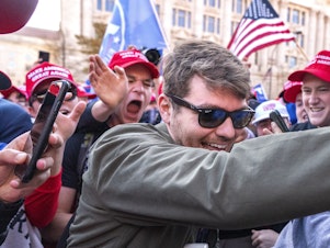 caption: Nick Fuentes, center, greets supporters before speaking at a pro-Trump march on Nov. 14, 2020, in Washington. Fuentes, who has been labeled a white supremacist and anti-Semite by the Anti-Defamation League, sat down for dinner with former President Trump and Ye, the rapper formerly known as Kanye West, last week.