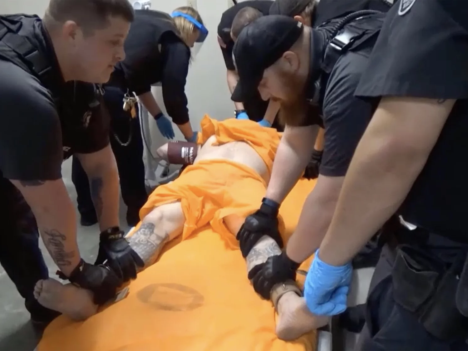 caption: A screenshot from a video of officers at the U.S. penitentiary in Thomson, Ill., holding an incarcerated person in a four-point restraint.
