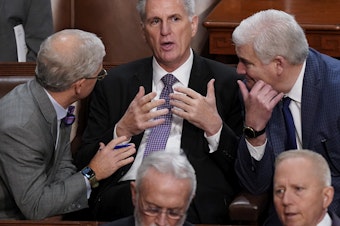 caption: Rep. Kevin McCarthy, R-Calif., is flanked by Rep. Patrick McHenry, R-N.C., left, and Rep. Tom Emmer, R-Minn., right, in the House chamber as lawmakers meet for a second day to elect a speaker and convene the 118th Congress.