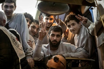 caption: People gesture from a Red Cross bus carrying Palestinian prisoners released from Israeli jails in exchange for hostages released by Hamas from the Gaza Strip, in Ramallah, in the occupied West Bank, on Sunday.